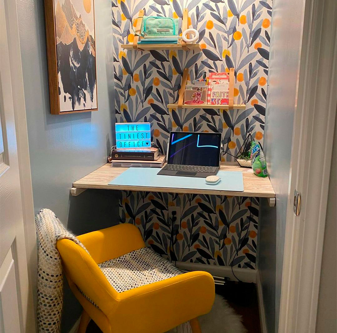 Compact home office idea with yellow chair and laptop on desk, featuring vibrant wallpaper for a productive work process.