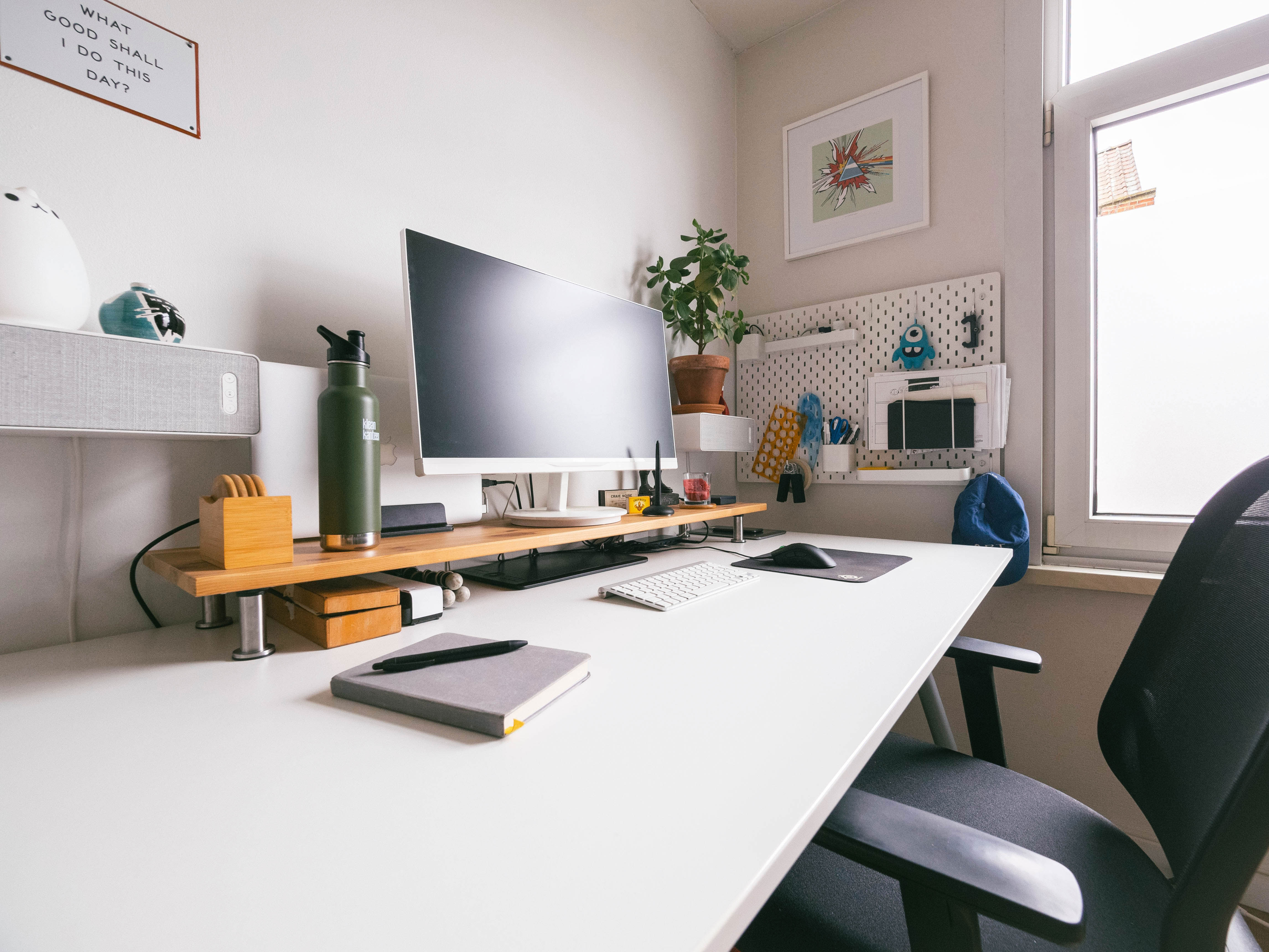 Modern home office setup with pegboard organization near table, computer monitor, and ergonomic chair for productive work environment