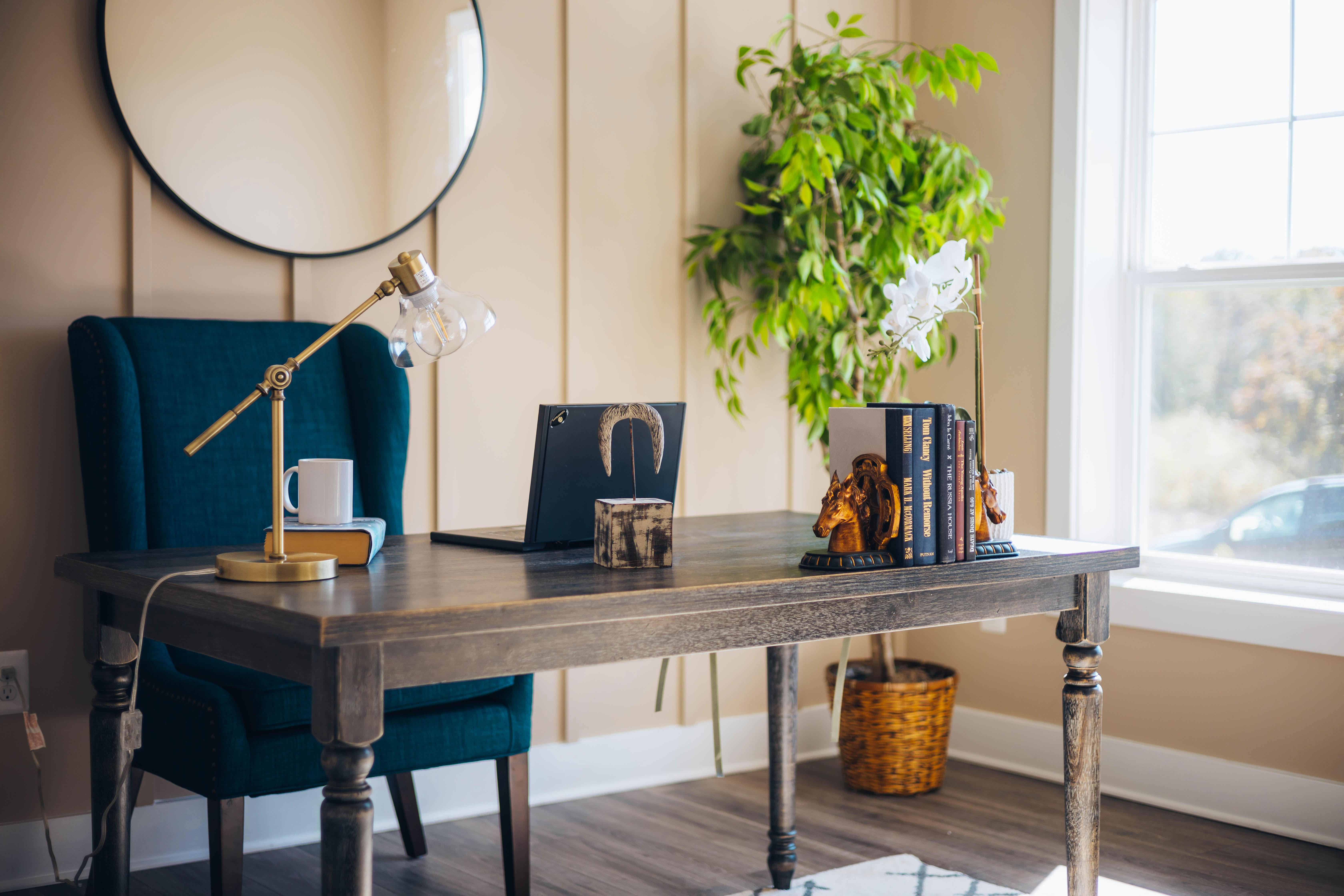 Laptop on brown wooden desk with decorative books and a lamp in a cozy home office setup for productivity.