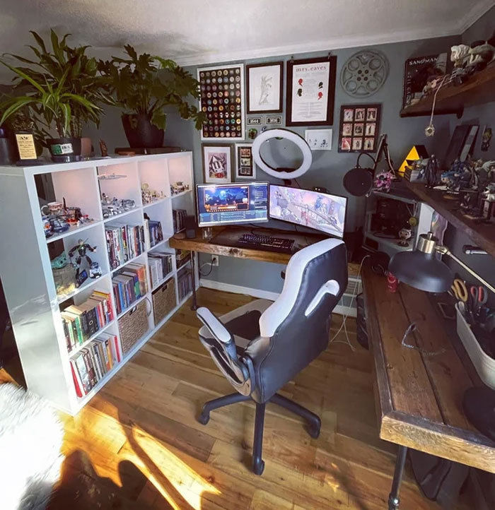 Home office with open shelves, dual monitors, wall pictures, and organized workspace for a productive work process.