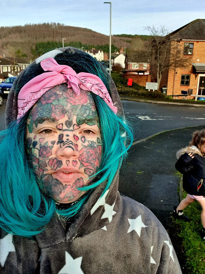 Mom with face tattoos, wearing blue hair and a pink bandana, outdoors. Mom with face tattoos, wearing blue hair and a pink bandana, outdoors.