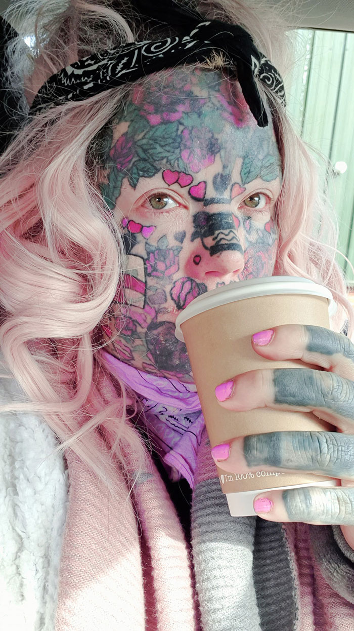 Woman with facial tattoos holding a coffee cup, showcasing body art detail. Woman with facial tattoos holding a coffee cup, showcasing body art detail.