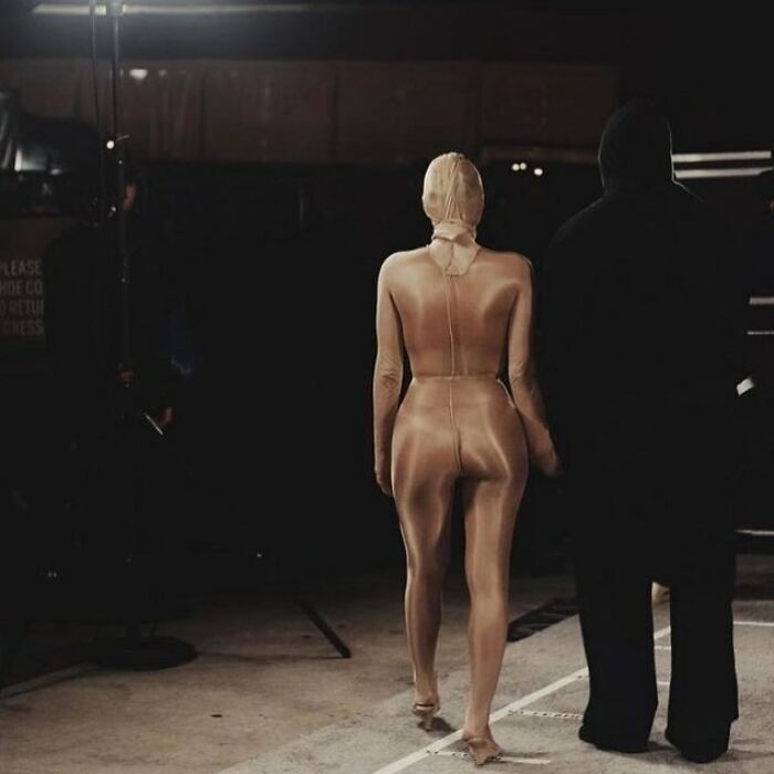 Bianca Censori in avant-garde fashion, walking with a person, showcasing designer influence.