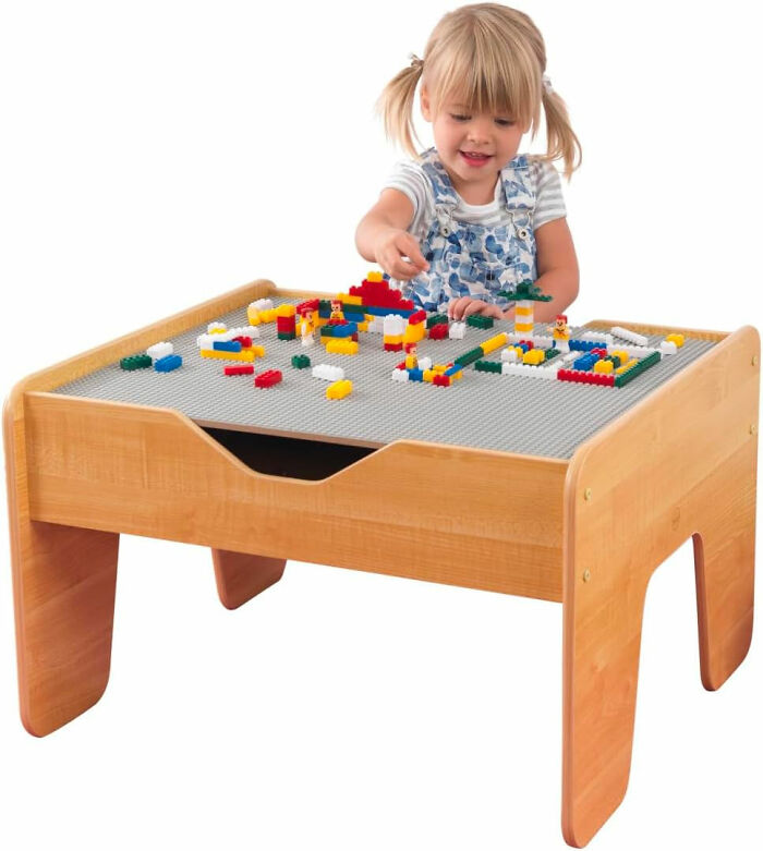 girl playing with legos at a wooden desk