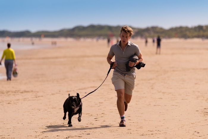 Person running on the beach with a dog on a leash, capturing a moment of energetic activity.