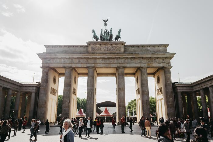 Brandenburg Gate in Berlin with tourists showcasing the best and worst things about countries in a busy urban setting.