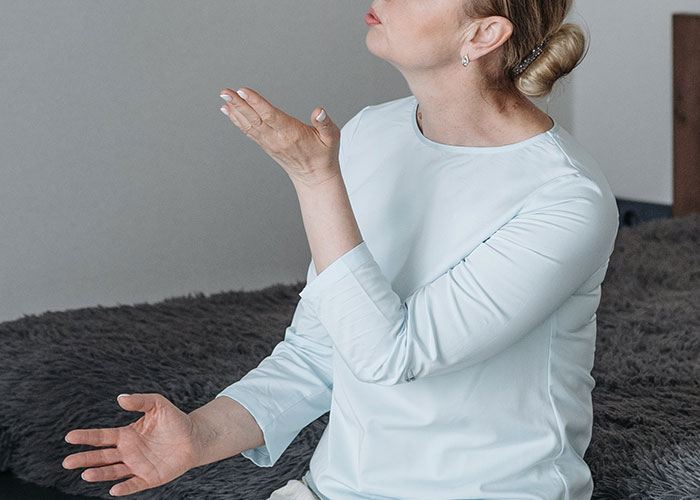 Woman in a white shirt emotionally gesturing in a room, reacting to a huge tattoo on her chest gift from MIL to baby.