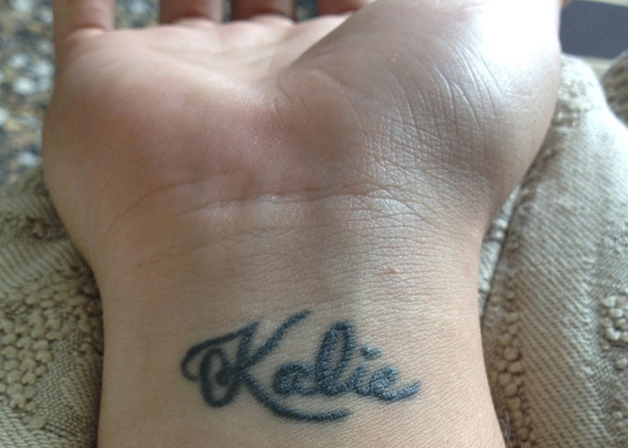 Tattoo of the name Katie inked on a wrist, showcasing a personal and meaningful huge tattoo on her chest concept.