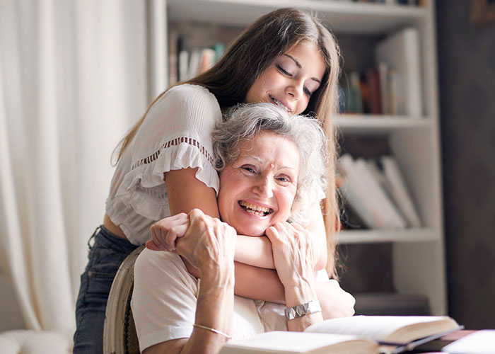 Grandmother and young woman smiling and hugging, symbolizing family connection and a huge tattoo on her chest story.