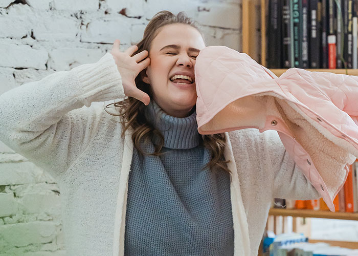 New mom holding a pink baby jacket, emotional in cozy setting, connected to a huge tattoo chest gift incident from MIL.