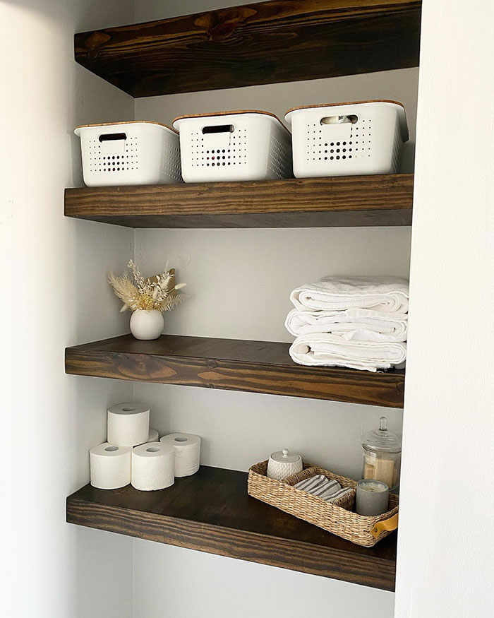 Dark walnut shelves stained in rich Minwax stain colors holding baskets, towels, and bathroom essentials in a corner.