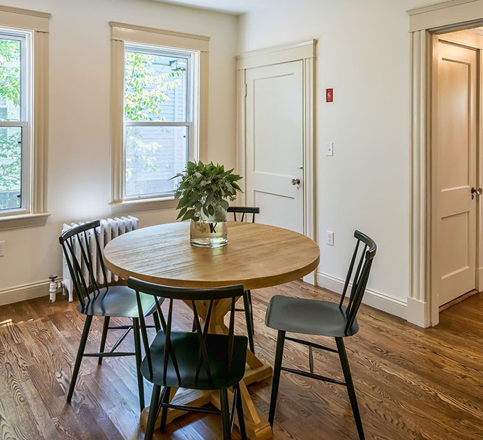 Round walnut table with Minwax stain colors in a bright white room surrounded by black chairs and natural light.