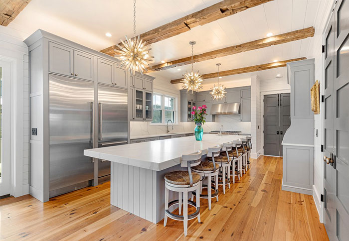 Bright and spacious beach style kitchen featuring modern kitchen design elements and timeless wooden beams.