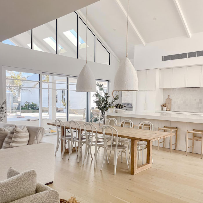 Spacious modern kitchen design with natural light, white cabinetry, wooden dining table, and minimalist decor for a timeless look.