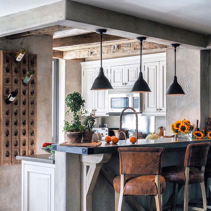 Modern kitchen design with unique personal touches, featuring rustic elements, potted plants, and leather bar stools.