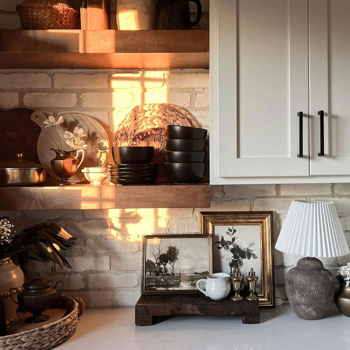 Modern kitchen designs featuring framed pictures, decorative items, and warm natural light on open shelves and counters.