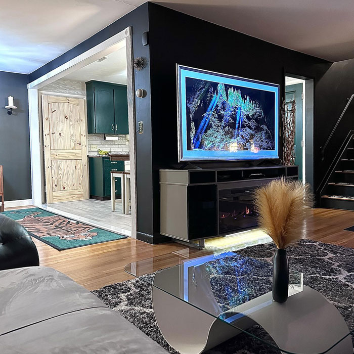 Open spaced room featuring a modern kitchen design with green cabinets and a stylish living area with black walls.