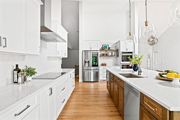 Spacious bright modern kitchen with multifunctional island, white cabinets, and stainless steel appliances for a timeless look