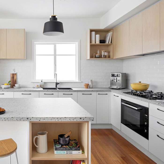 Bright modern kitchen featuring multiple wood tones, white cabinets, and terrazzo countertops for a timeless look.