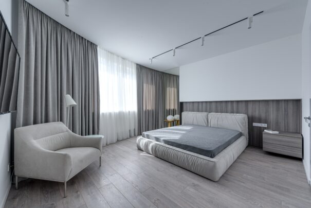 Minimalist bedroom with concrete accent wall and DIY modern floating nightstand beside the bed under natural light.