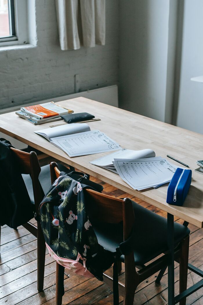 Classroom desk with papers, backpacks on chairs, and study materials highlighting challenges of getting rich in countries.