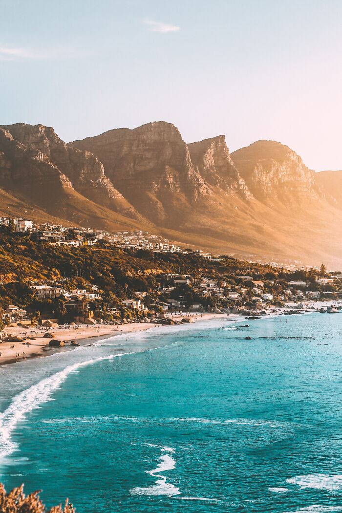 Coastal town with mountains and beach at sunset, highlighting the best and worst about countries' landscapes.