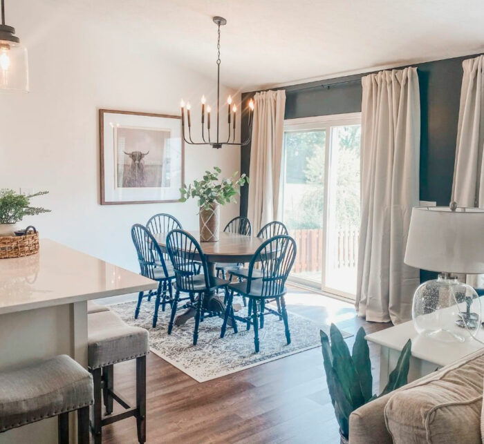 Round dining table with blue chairs near large window in bright room painted with Sherwin-Williams paint colors 2024.