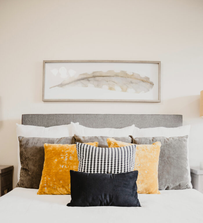 Bed with pillows featuring Sherwin-Williams paint colors in gray and warm tones for a cozy 2024 look