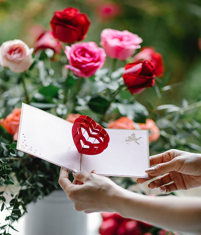 Woman with Valentine card near flowers