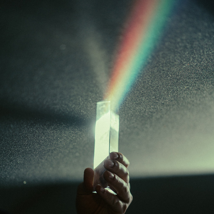 Person holding a prism casting a rainbow light illustrating warm colors in creative decor ideas and design. Person holding a prism casting a rainbow light illustrating warm colors in creative decor ideas and design.