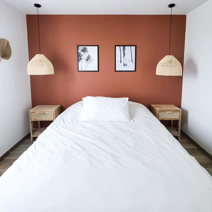 Bedroom featuring warm colors with a terracotta accent wall and white bedding in a minimalist decor setting. Bedroom featuring warm colors with a terracotta accent wall and white bedding in a minimalist decor setting.
