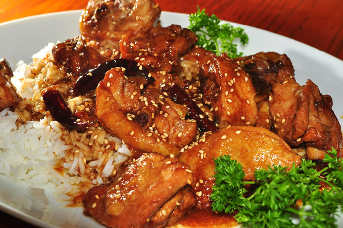 Plate of cooked chicken with sesame seeds and chili peppers served with white rice and parsley garnish on a forum cooking fails discussion.