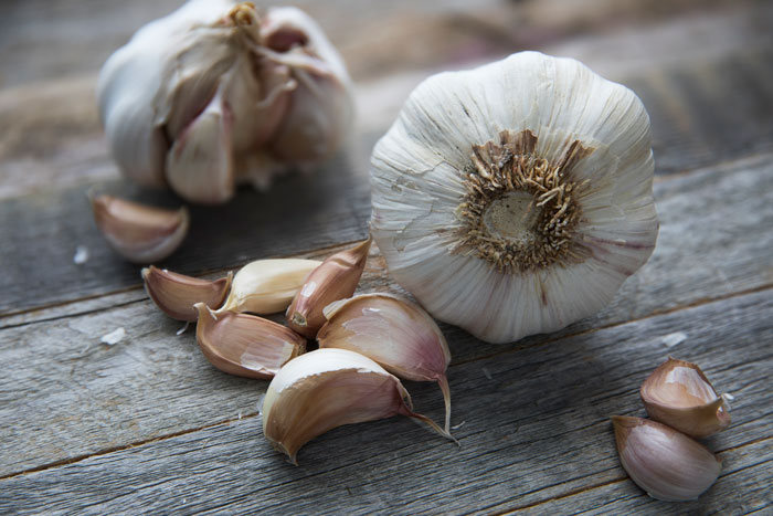 Close-up of garlic cloves and bulbs on wooden surface representing cooking fails shared by an online community forum.