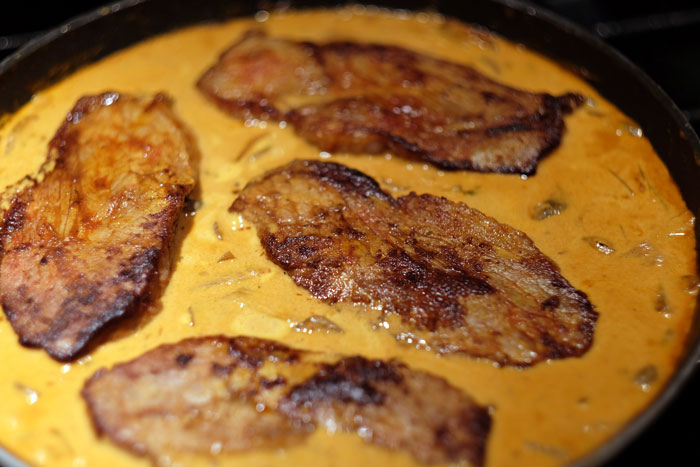 Seared meat cooking in a creamy sauce illustrating unexpected cooking fails shared by online community forum users.