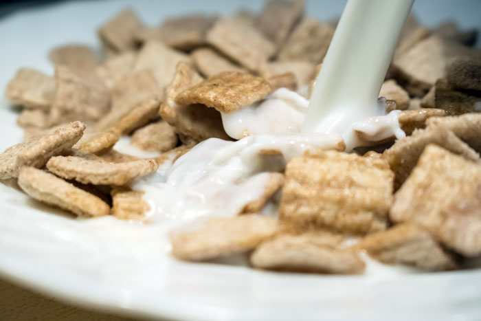 Close-up of milk pouring over cereal squares in a bowl, illustrating common cooking fails shared by an online community forum.