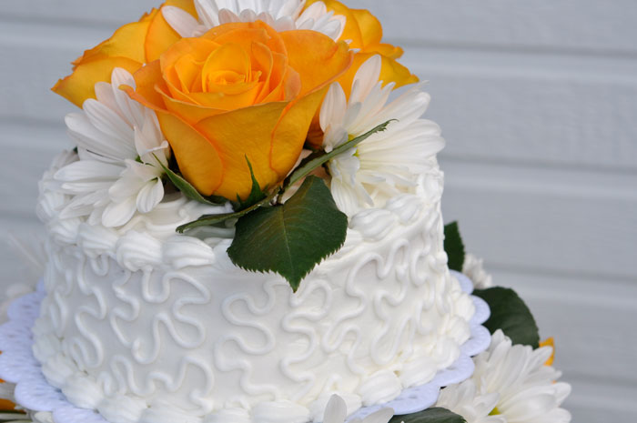 White frosted cake decorated with yellow roses and white daisies, highlighting unexpected cooking fails shared in an online community forum