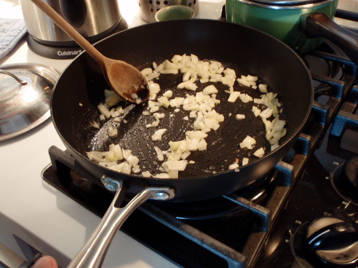 Sautéing chopped onions in a black pan on a stove, illustrating common cooking fails shared by online community users.