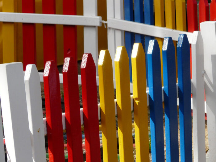 A picket fence with white, red, yellow, and blue panels A picket fence with white, red, yellow, and blue panels