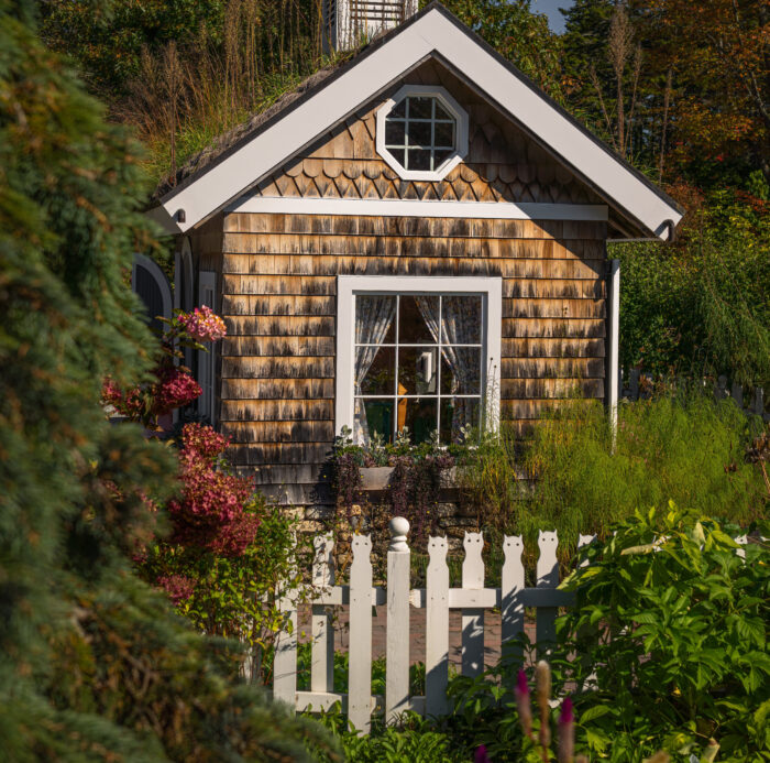 A white picket fence shaped like a cat on top A white picket fence shaped like a cat on top