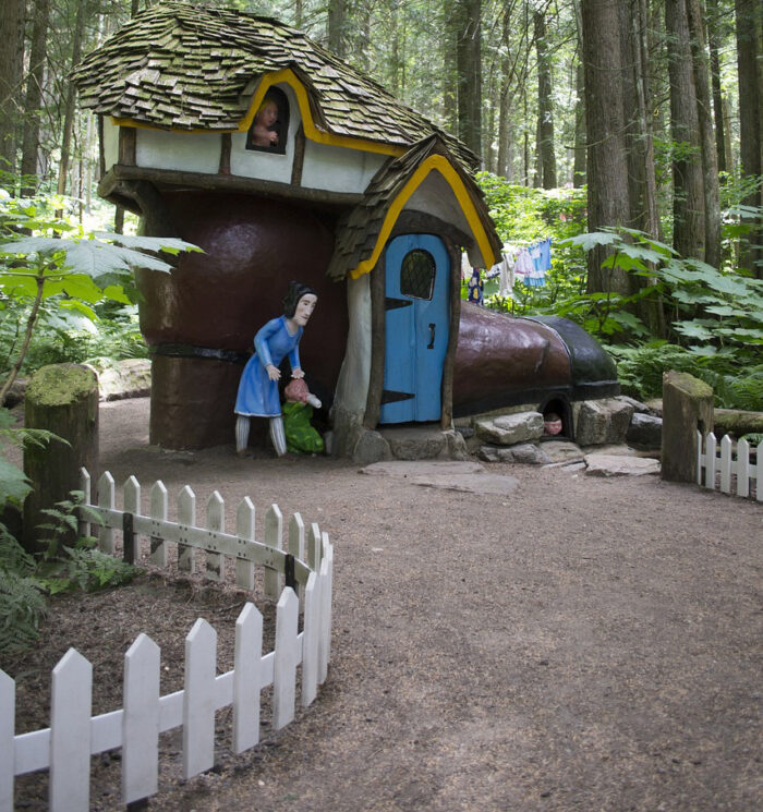 A curved white picket fence near a fairy tale house A curved white picket fence near a fairy tale house