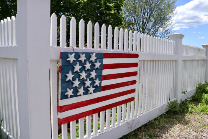 An American flag on a white wooden fence An American flag on a white wooden fence