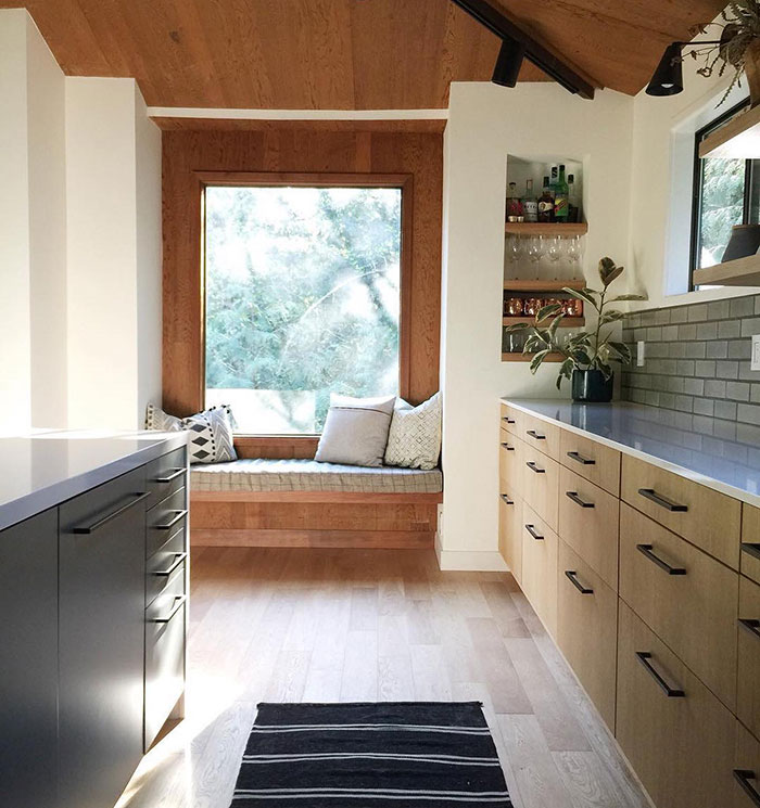 Cozy kitchen window seat with natural wood accents and soft cushions creating a warm and inviting space in the home.