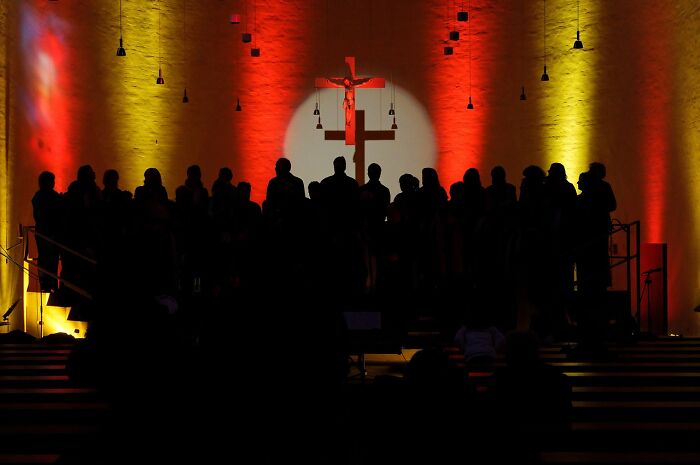 Silhouetted wedding guests in a church with colorful lighting, evoking thoughts of weddings and possible divorce signs.