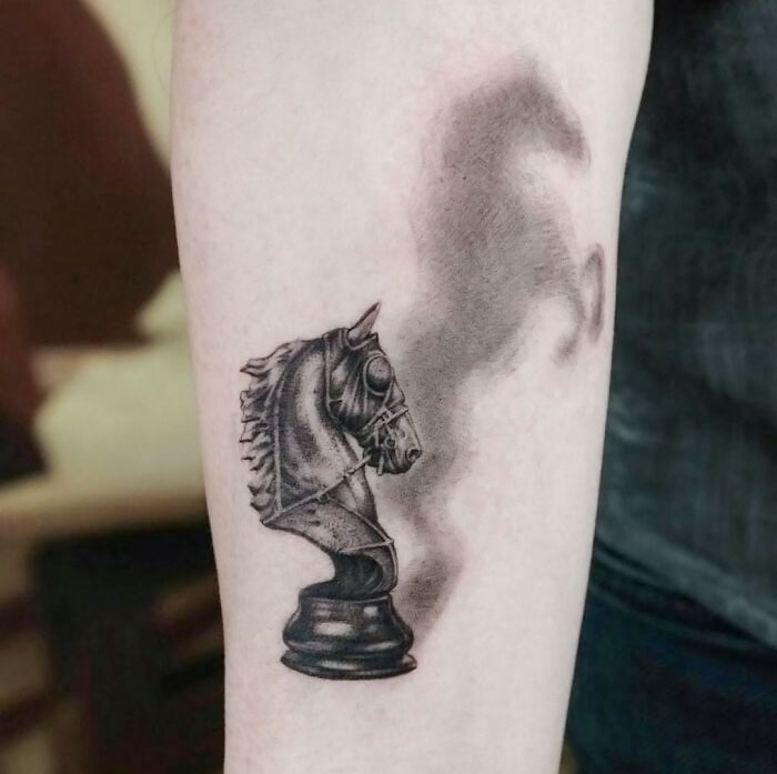 3D tattoo of a chess knight with shadow effect on forearm showcasing artistic detail.