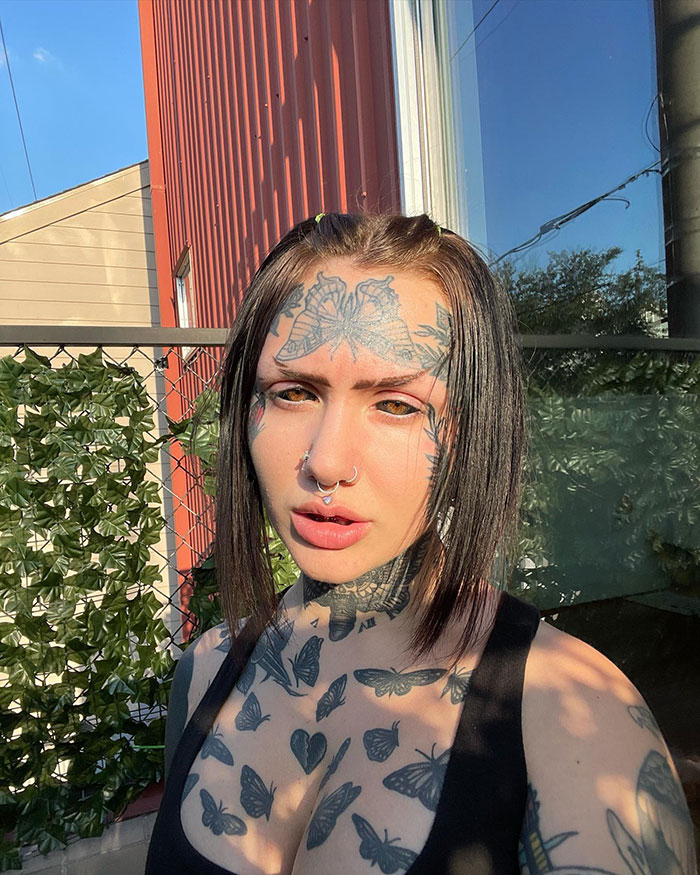 Woman with extensive tattoos outdoors, showcasing her inked look.