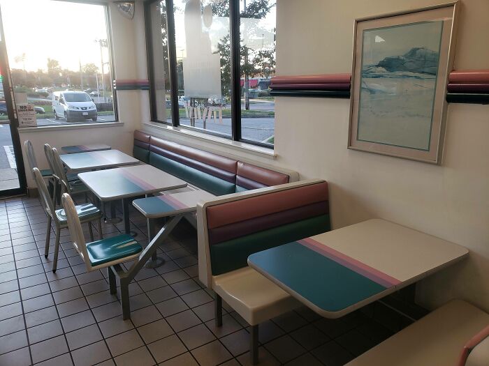 Retro ’90s diner interior with pastel-colored booths and tables, evoking nostalgia.