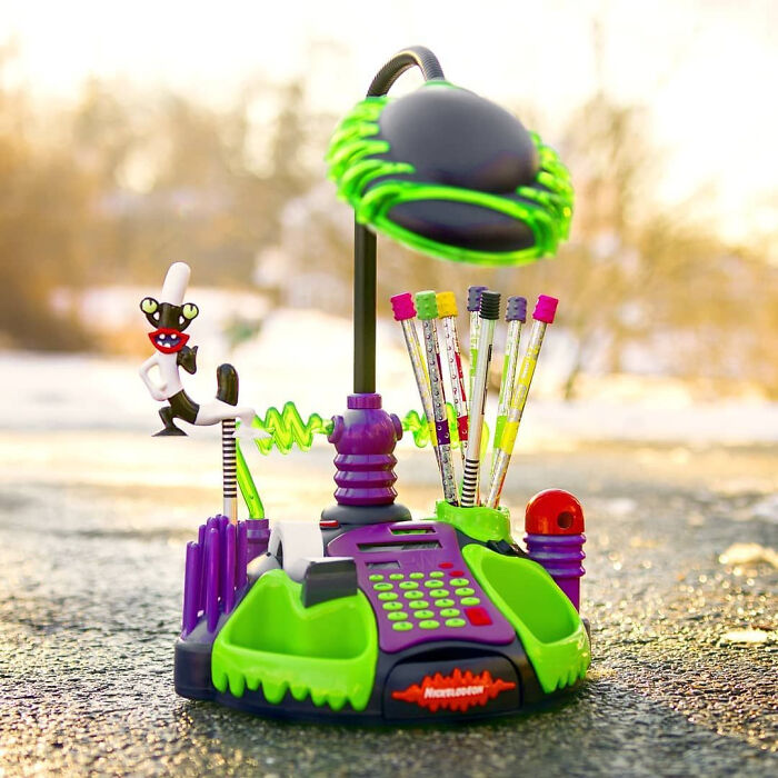 '90s nostalgia with a colorful Nickelodeon-themed desk accessory set including pens and a lamp outdoors.