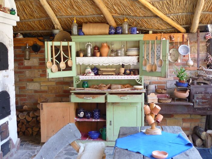 Vintage kitchen featuring distressed green kitchen cabinets with natural wooden utensils and rustic decor.