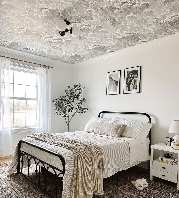 White bedroom featuring expert-approved home design with wallpaper ceiling, gray sheets, and minimalist decor.
