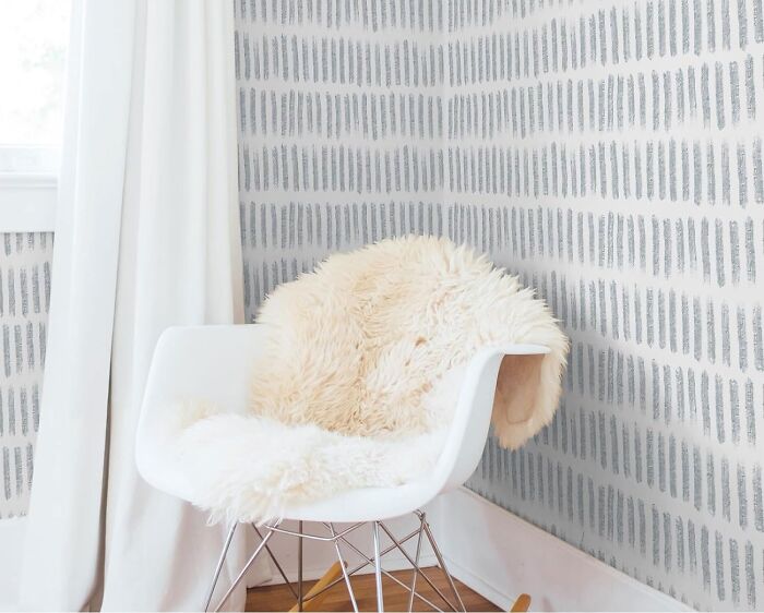 Room with gray line wallpaper and white chair with rug